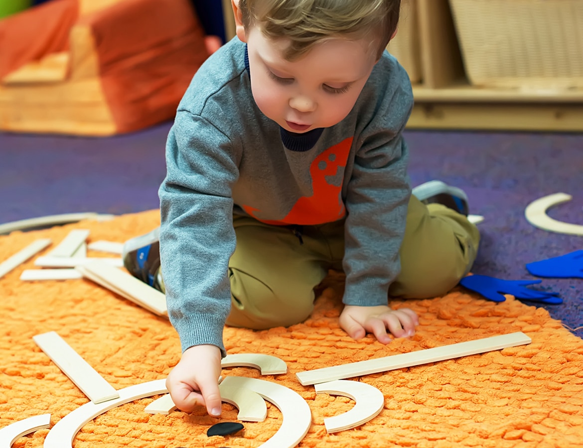 Toddler playing on a matt in preschool